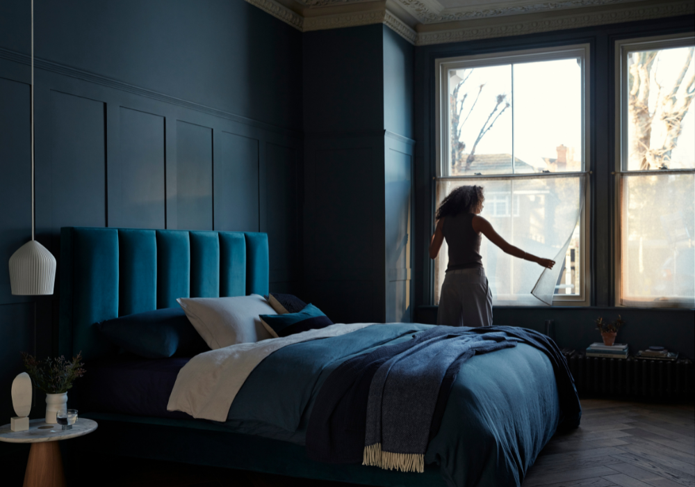 Woman in dark bedroom closing the window blinds